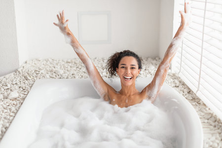 Woman Enjoys a Relaxing Bubble Bath in a Cozy Bathroom With Bright Natural Lightの写真素材