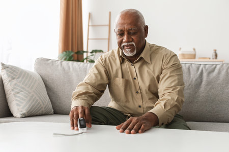 Senior Man Measures Blood Pressure at Home During Morning Routine for Health Monitoring and Self-Careの写真素材
