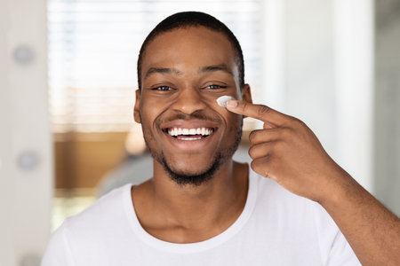 Man Applying Skincare Product While Smiling in Bright Indoor Setting