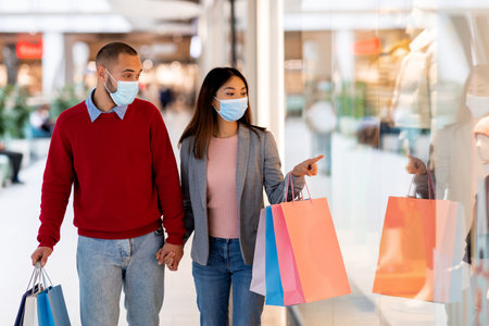 Couple Enjoys Shopping Together in a Mall While Wearing Face Masks During the Afternoonの写真素材