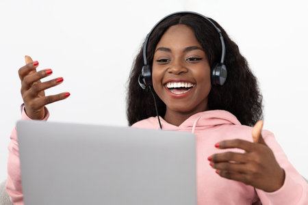Young Woman Engaged in a Video Call While Smiling and Wearing Headphones at Home During the Dayの写真素材