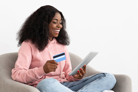 Excited Woman Shopping Online With Tablet and Credit Card While Sitting Comfortably at Homeの写真素材