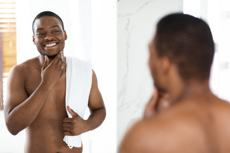 Man Enjoys Grooming Routine in Bright Bathroom While Smiling in Mirrorの写真素材