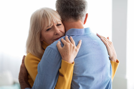 Emotional Hug Between Elderly Couple in a Bright Room Showcasing Love and Support During a Difficult Momentの写真素材