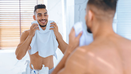 Man Enjoying Morning Routine While Drying His Face in Modern Bathroom Mirrorの写真素材