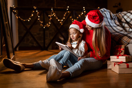 Mother and Daughter Enjoying a Cozy Christmas Evening While Drawing Together at Homeの写真素材