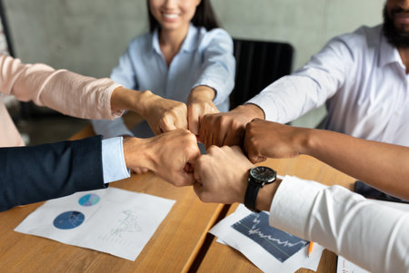 Team Members Celebrate Success With Fist Bumps in Modern Office Settingの写真素材