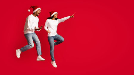 Joyful Couple Celebrating Christmas With Enthusiasm While Wearing Matching Santa Hats and Casual Outfits in a Festive Atmosphereの写真素材