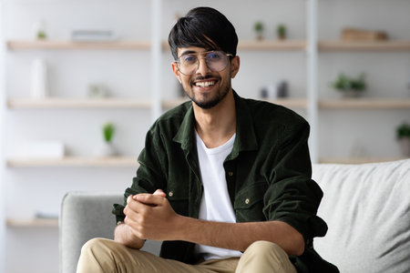 Smiling Young Man Seated on a Couch in a Cozy Living Room With Modern Decorの写真素材