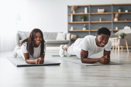Young black couple planking together in living room
