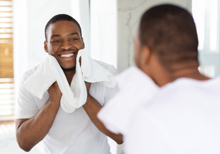 Man Smiling and Grooming Himself in a Bright Bathroom While Holding Towelsの写真素材