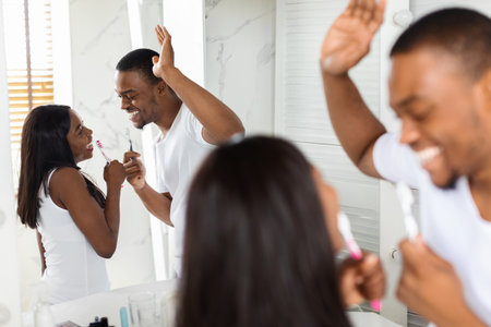 Couple Enjoys Playful Morning Routine While Brushing Teeth Together in a Bright Bathroomの写真素材