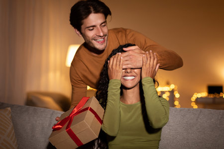 Boyfriend Surprises Girlfriend With Gift at Home During Anniversary Celebration in the Eveningの写真素材