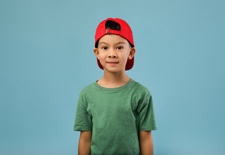 Young Boy With a Red Cap Smiling Against a Blue Background