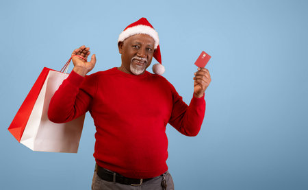 Man Wears a Santa Hat and Holds a Shopping Bag and Credit Card During Holiday Seasonの写真素材