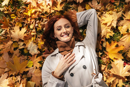Woman Relaxes on Colorful Autumn Leaves in a Serene Parkの写真素材
