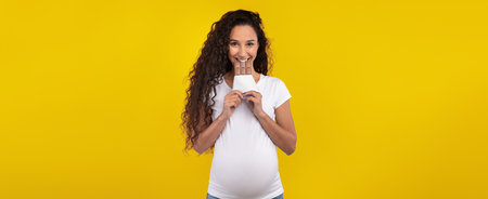 Pregnant Woman Smiling While Holding a Pregnancy Test in Front of a Bright Yellow Background