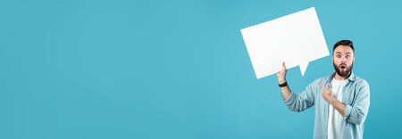 Man Expressing Surprise While Holding a Blank Speech Bubble Against a Blue Background
