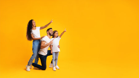 Family Enjoying a Playful Moment Together Against a Bright Yellow Background While Pointing and Smilingの写真素材