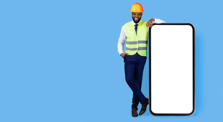Professional Man in Safety Gear Poses Beside a Large Blank Smartphone on a Blue Background