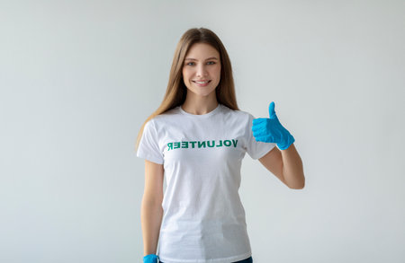 Positive Lady Showing Thumbs up With Blue Gloves on Light Backgroundの写真素材