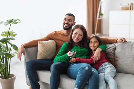 Happy Young Arab Family Enjoys Time Together Watching Television in Their Living Roomの写真素材