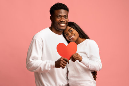Happy Couple Celebrates Love With Red Heart Over Pink Background in Casual Attire
