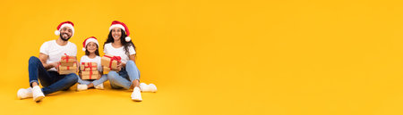 Family Celebrating Christmas With Gifts and Holiday Spirit in Front of a Bright Yellow Backgroundの写真素材