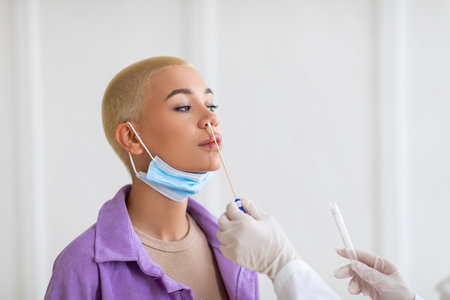 Doctor making covid-19 PCR test for female patient, free space. Young lady undergoing coronavirus diagnostic procedureの写真素材