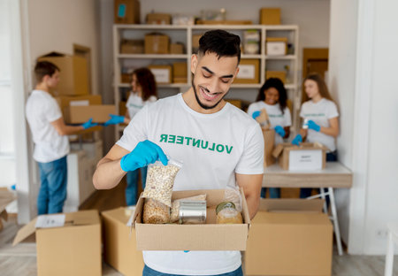 Millennial Male Volunteer Smiles While Holding Food Donation Box at Charity Center