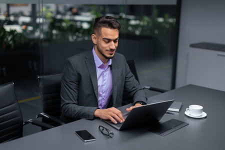 Businessperson Works on Laptop at Desk in Modern Office During Daytime