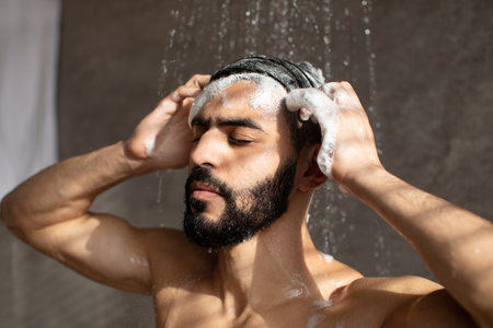 Handsome Young Arabic Male Model Enjoying a Refreshing Shower While Washing His Hairの写真素材