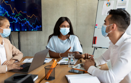 Business Colleagues in Masks Discussing Strategies During Corporate Meeting in Boardroomの写真素材