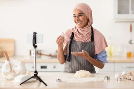 Cooking Demonstration With a Smiling Chef Wearing a Hijab in a Bright Kitchen Settingの写真素材