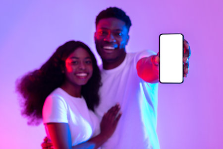 Couple Showcasing Smartphone Mockup for New App in Vibrant Neon Light Settingの写真素材