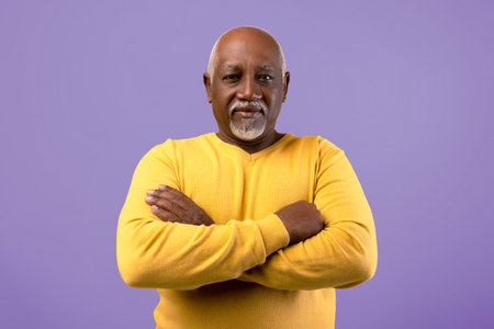 Man With Crossed Arms Stands Against a Purple Background Wearing a Yellow Sweater