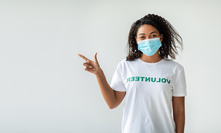 Young Female Volunteer Gestures Towards Copy Space for Medical Initiative Promotion