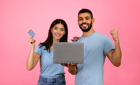 Happy Couple Celebrating Online Shopping Success With Laptop and Credit Cardの写真素材