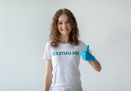 Happy Volunteer Showing Thumbs up Against Light Background in Studio Setting