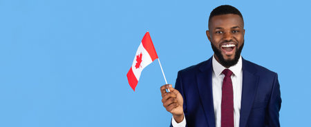 Smiling Man in Suit Holding Canadian Flag Against Blue Background During Celebrationの写真素材
