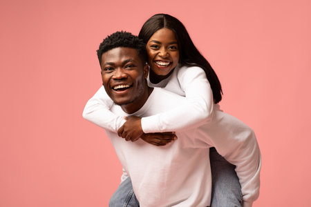 Happy Couple Enjoying a Playful Moment in Pink Studio Setting, Smiling and Laughing Togetherの写真素材