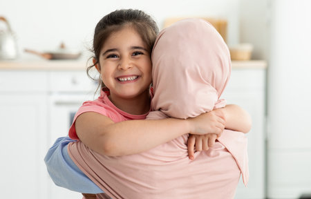 Happy Little Girl Embracing Her Muslim Mom In Hijab At Home, Closeupの写真素材