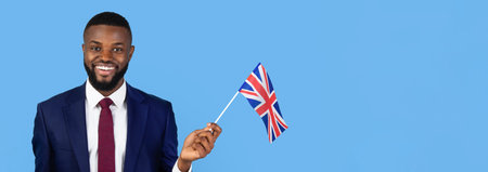 Man in Suit Happily Holding British Flag Against Blue Backgroundの写真素材