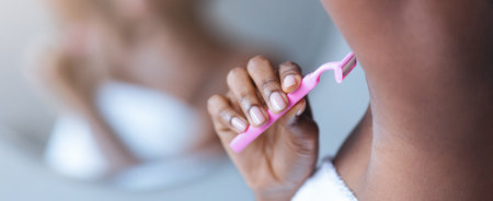 Woman Brushing Teeth in Bathroom While Wearing Towel in Morning Lightの写真素材