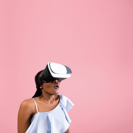Shocked woman wearing VR helmet, experiencing virtual reality on pink background