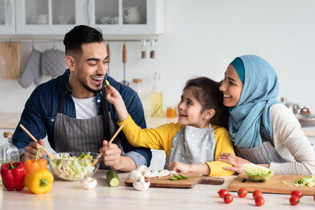 Taste It. Cute little arab girl feeding her daddy with cucumber slice