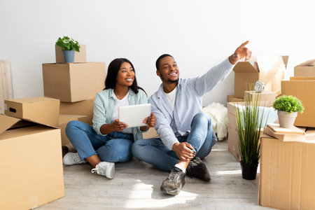 Excited african american couple with digital tablet buying online household goods for their home and...