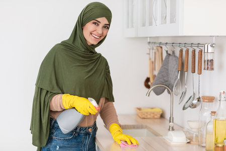 Cheerful muslim young woman cleaning dining table at kitchenの写真素材