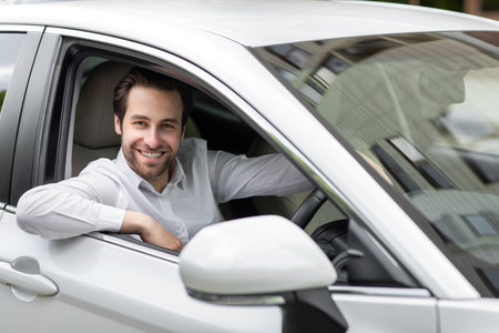 Portrait of smiling young man, driving his own new car through city during morning commute
