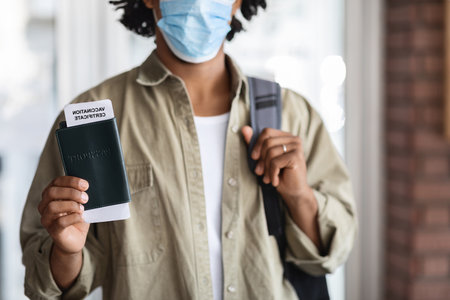 Pandemic Travels. Black Male Traveller Holding Passport With Vaccination Certificate Document Insideの写真素材